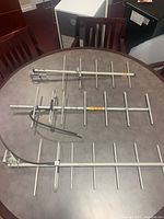 Three Sinclair Yagi directional antennae laid out on a round table, showing their lengths and structure of elements, with coax cables affixed to two.