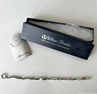 Photo of Aitkens Pewter bracelet with branded box and token on white background.