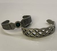 Two pewter Irish Celtic style cuff bracelets displayed on white surface