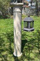 Full view of the antique porch pillar standing upright outside in daylight, showing front and side angles with some natural shadows and a garden background.