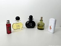 Photo showing all 5 cologne bottles from left to right: red rectangular Ralph Lauren bottle #2, clear Sexual Secret Man, black Sexual Noir, green spray bottle, and white rectangular Ralph Lauren bottle with Polo logo