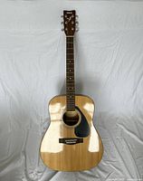 Front view of Yamaha F310 acoustic guitar showing natural wood top with black pickguard and six strings.