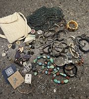 Overhead view showing the full assortment of vintage jewelry items and white beaded shoulder purse scattered on a textured floor.