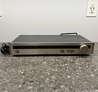 Front view of Luxman AM/FM stereo tuner T-210L showing power button, frequency display, and tuning knob