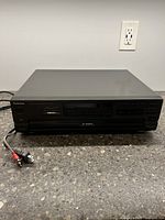 Front view of the Technics CD changer showing power switch and RCA cable connections.
