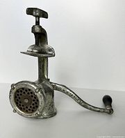 Side view showing the full meat grinder mounted on the table clamp with the handle extended horizontally.