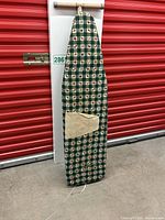 Ironing board standing upright showing full cover and pocket on front.