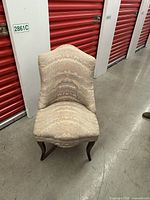 Front view of the antique upholstered side chair showing the patterned fabric and curved wooden legs