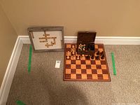 Overall view showing the chess board, wooden box with chess pieces inside, and the framed Scrabble tile art leaning against the wall.