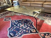 Full view of clear bent glass coffee table on rug in living room