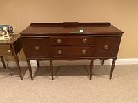 Front view of sideboard showing two central drawers, two cabinet doors and turned legs