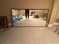 Front view of large rectangular mirror leaning against wall, showing size and frame details.