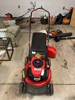 Front view of mower showing red steel deck, recoil starter, front wheels and engine housing