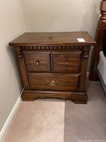 Front view of one Kroehler pine night stand showing two small upper drawers with wooden knobs and one larger lower drawer with brass handle.