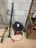 Full view of red and black 4 gallon shop vacuum, flexible hose, extension wand, and power cord.