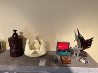 Wide view showing full lot of assorted souvenir and collectible items on shelf, including the carved wood jar, candle holder, fish figure, agate slice, Cloisonne balls, and other small decorative items.