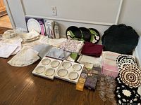 Wide view of all items in the lot including linens, napkin rings, cocktail shaker, plates, candles, coasters.