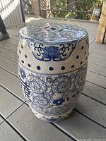 Front perspective of barrel-shaped garden stool on wood deck, showing body and top details