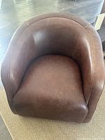 Angled front view of one brown leather swivel chair