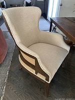 Front and side view of beige burlap upholstered armchair with oak frame and nailhead trim