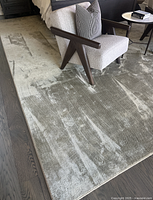 Rug under chair and bed showing overall color, pile, and placement on floor.
