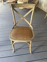 Front view of one outdoor X-back chair showing wood frame and woven seat