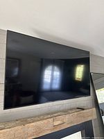 Front view of Samsung TV mounted on wall with wooden mantel below