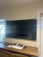 Front view of wall-mounted TV atop wooden cabinet with remote control on surface