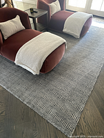 Rug on hardwood floor beneath two red velvet chaise lounges showing overall appearance and condition