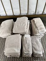 A photo showing multiple stacks of sand-colored Sheridan towels of various sizes, including bath, hand, and face towels, neatly folded on the floor.