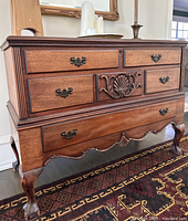 Full view of the dresser showing six drawers, central carved shell motif, wood finish, and metal drawer handles.