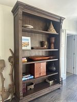 Front view showing four-shelf open bookcase with decorative top molding