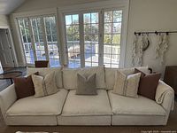 Front view of white linen sofa with five throw pillows in living room