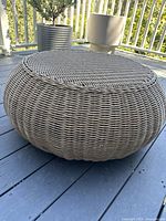 Side/front view of round wicker ottoman on deck