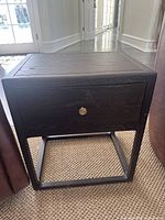 Front view of a dark wood side table with a drawer and metal base frame
