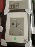 Two sealed IKEA VIRSERUM picture frames stacked, with visible packaging and protective corners