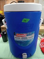 Front view of blue Coleman 5 gallon water cooler with white lid, displaying brand logo and capacity label