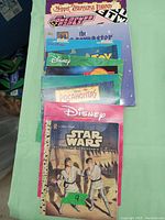 Photo of 11 collectable books stacked showing titles including Muppet Treasure Island, Powerpuff Girls, Disney classics, and Star Wars.