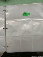Open binder with transparent plastic card sleeves displayed with multiple pockets per page for collector card storage.