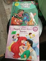 Photo of two Disney books: Friendship Stories and Happily Ever After Stories, showing colorful covers with classic Disney characters and sticker count