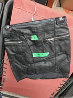 Black ladies skirt size 2 with zipper pockets laid flat on pink surface for detail and condition inspection.