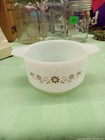Front side view showing the brown floral pattern on white milk glass Pyrex bowl with two handles