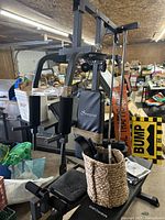 Full view of Soozier home gym with frame, padded seat, and exercise arms in a cluttered room.