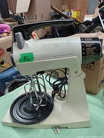 Side view of the vintage Sunbeam Mixmaster stand mixer showing cream color, beaters attached, and base.