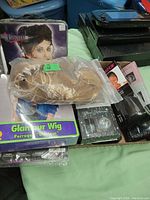 Multiple wigs and wig accessories displayed side by side, including boxed wigs and some loose in packaging.