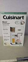 Front of original box showing Cuisinart Mix It In soft serve ice cream maker with graphics depicting ice cream, cone holder, and mix-ins dispenser.