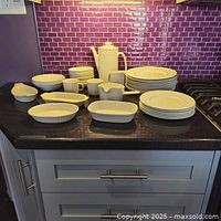 Full set arranged on kitchen counter showing plates, bowls, cups, serving dishes, coffee pot, and creamer in Johnson Brothers Athena pattern.