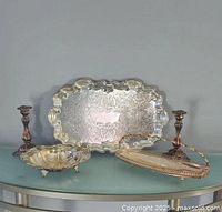 Photo showing full lot on table: silver plated tray, two candlesticks, footed bowl, and oval basket.
