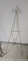 Full view of the metal easel showing the triangular frame and trefoil decorative top.