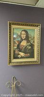Framed vintage Mona Lisa needlepoint tapestry hung on wall showing full front view.
